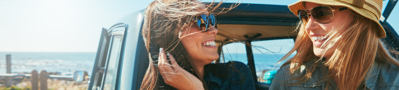 two friends smiling while sitting in back of car